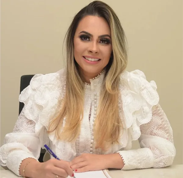 Dra. Milene Pinhatari sentada à mesa do consultório